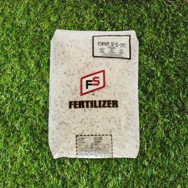 A bag of FS fertilizer rests on lush green grass, featuring branding and nutrient information prominently displayed on the package.