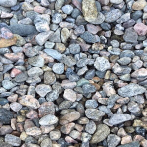 A close-up of variously colored small pebbles and rocks, displaying a mix of textures and shades of gray, pink, and brown.