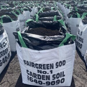 Large white bags filled with garden soil, labeled "Fairgreen Sod No. 1," are arranged in rows on a dirt surface.