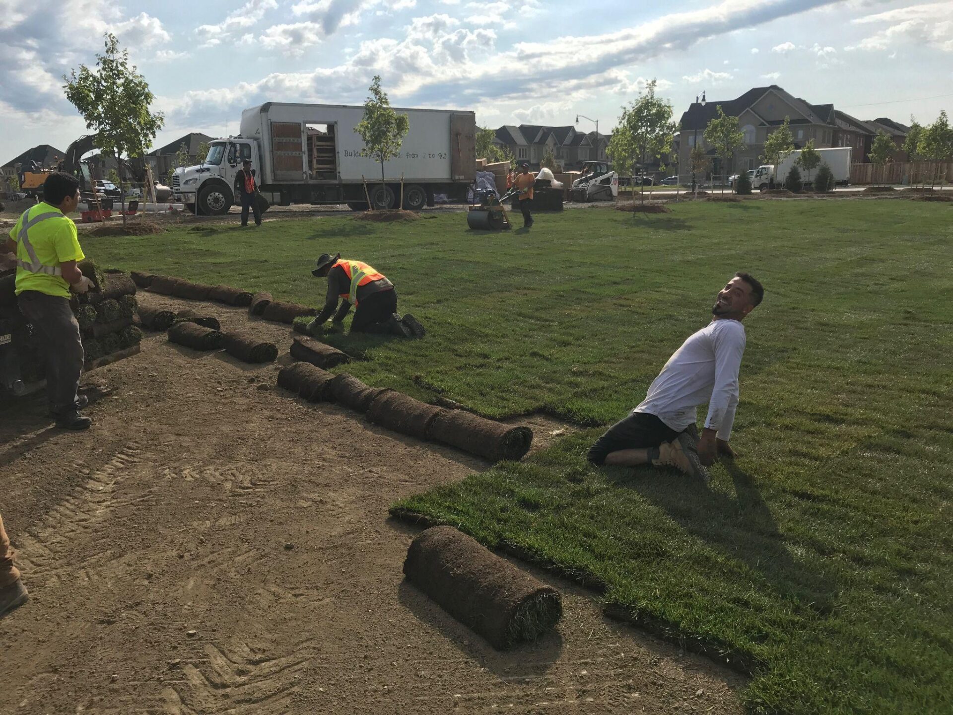 Crew laying sod on a new lawn in a residential area.